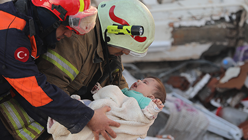 A baby is pulled from the rubble by rescue workers
